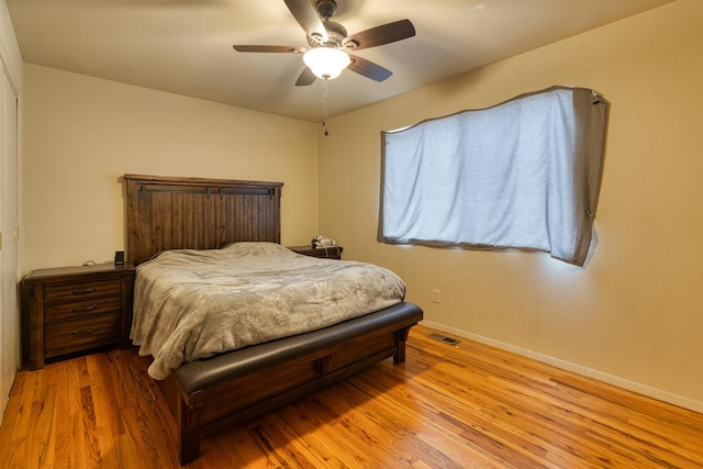 bedroom with visible vents, a ceiling fan, baseboards, and wood finished floors