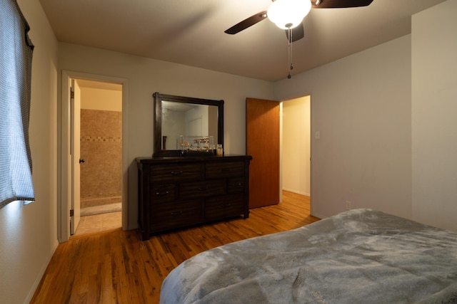 bedroom with a ceiling fan, ensuite bath, and wood finished floors