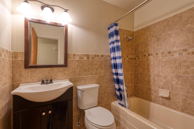 full bathroom featuring vanity, shower / bathtub combination with curtain, tile walls, toilet, and a textured wall