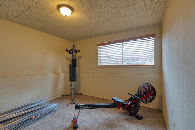 workout room with carpet flooring, a textured wall, and baseboards