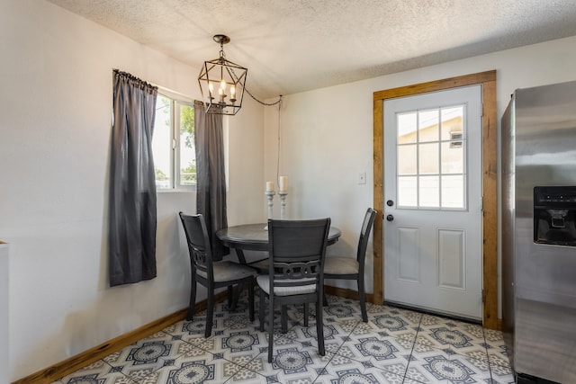 dining area featuring a textured ceiling, an inviting chandelier, and baseboards