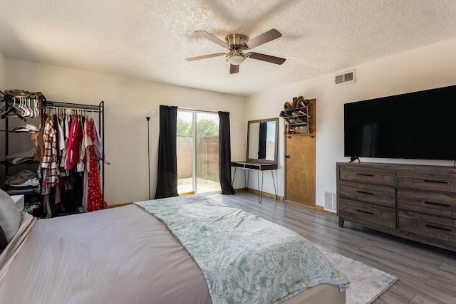 bedroom featuring visible vents, access to exterior, wood finished floors, and a textured ceiling