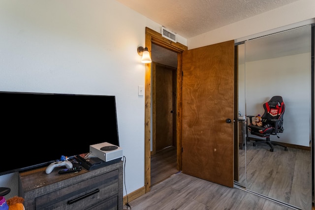 bedroom featuring visible vents, baseboards, wood finished floors, and a textured ceiling