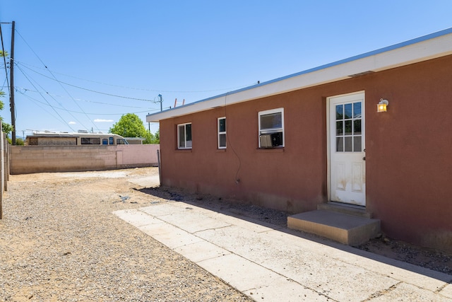 view of side of home featuring entry steps, fence, cooling unit, and stucco siding