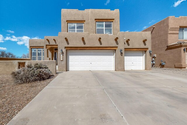 1001 Calle Garza NE, Albuquerque, NM 87113 - pueblo-style home with concrete driveway, a garage, and stucco siding