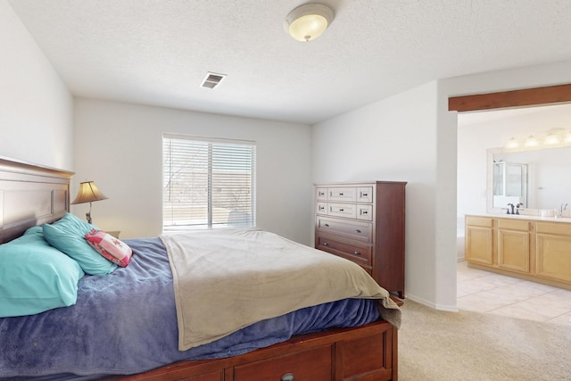 1001 Calle Garza NE, Albuquerque, NM 87113 - bedroom with baseboards, visible vents, a textured ceiling, light carpet, and connected bathroom