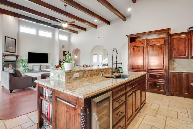 901 12th Ave SE, Rio Rancho, NM 87124 - kitchen featuring a sink, a ceiling fan, arched walkways, beamed ceiling, and a kitchen island with sink