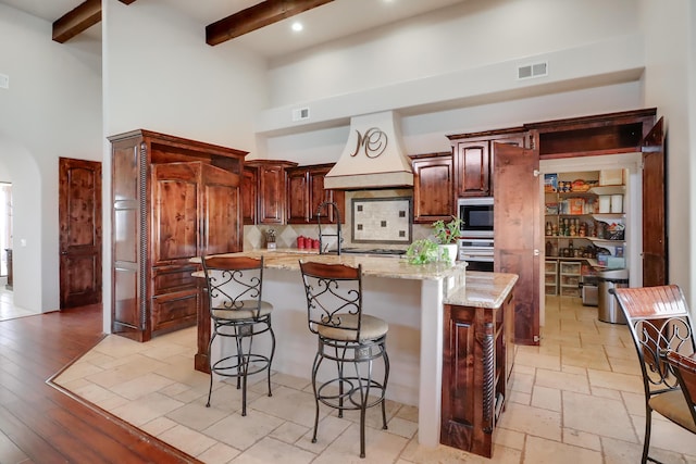 901 12th Ave SE, Rio Rancho, NM 87124 - kitchen with a towering ceiling, custom exhaust hood, tasteful backsplash, beamed ceiling, and a kitchen bar