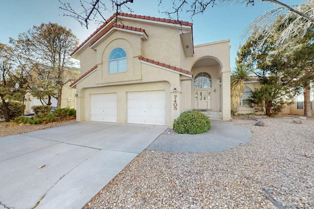 mediterranean / spanish house featuring concrete driveway, a tiled roof, a garage, and stucco siding