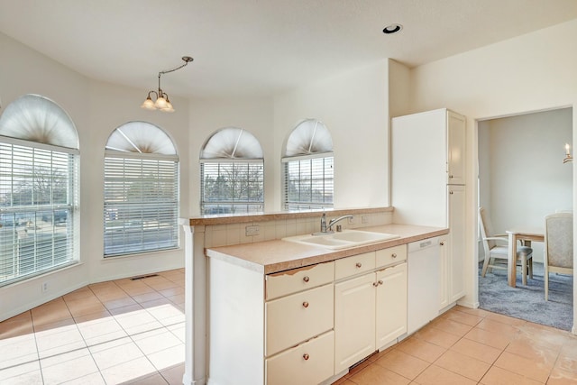 kitchen with a sink, dishwasher, a healthy amount of sunlight, and light tile patterned floors