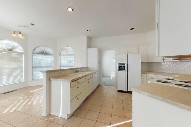 kitchen with a sink, white appliances, light tile patterned flooring, white cabinets, and decorative backsplash