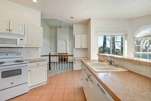 kitchen with a sink, backsplash, white cabinetry, white appliances, and light countertops