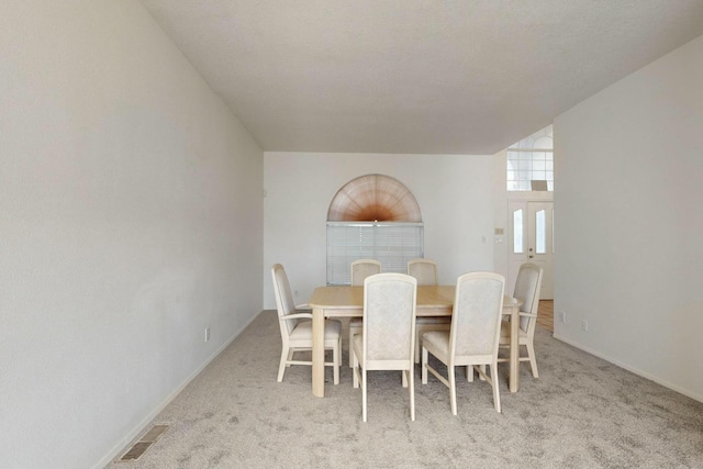 carpeted dining space featuring visible vents and baseboards