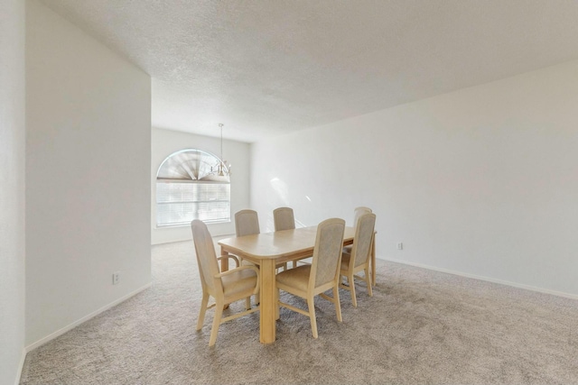 dining space with baseboards, a textured ceiling, carpet, and an inviting chandelier