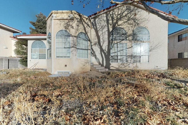 mediterranean / spanish home with stucco siding, a tile roof, and fence