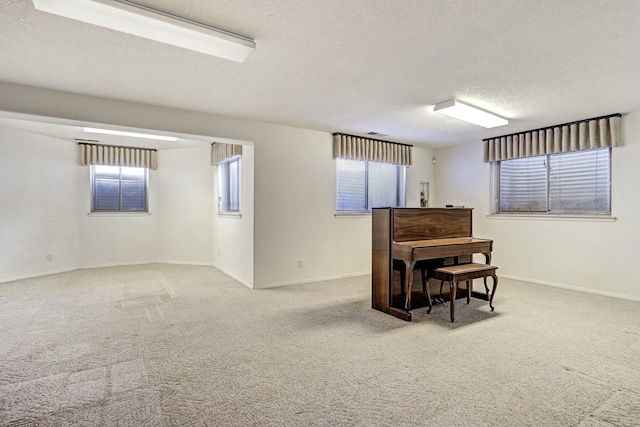 basement featuring a wealth of natural light, baseboards, carpet floors, and a textured ceiling