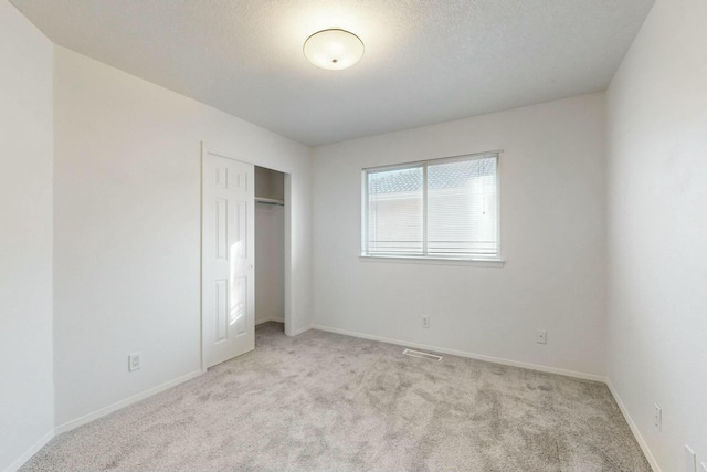 unfurnished bedroom with baseboards, visible vents, a closet, and light carpet