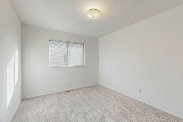 carpeted empty room with visible vents and baseboards