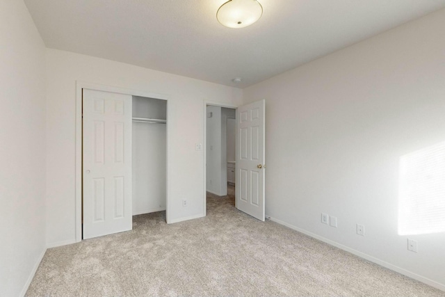 unfurnished bedroom featuring baseboards, a closet, and light carpet
