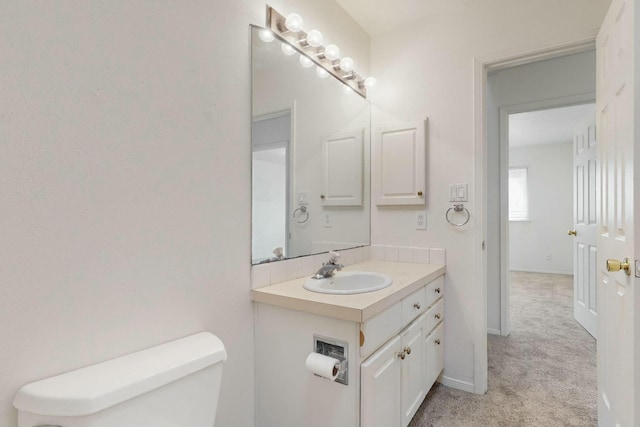 bathroom with toilet, vanity, and baseboards