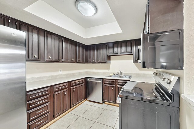 kitchen with light tile patterned floors, a raised ceiling, a sink, light countertops, and stainless steel appliances