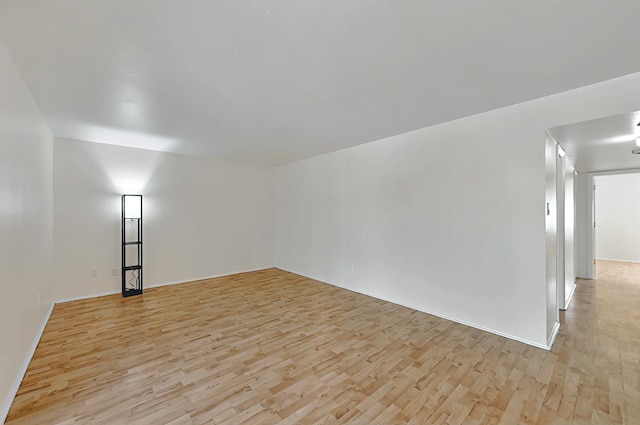 spare room featuring baseboards and light wood-type flooring