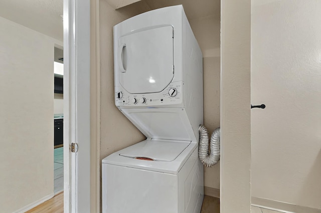 laundry area with laundry area, baseboards, and stacked washer / dryer