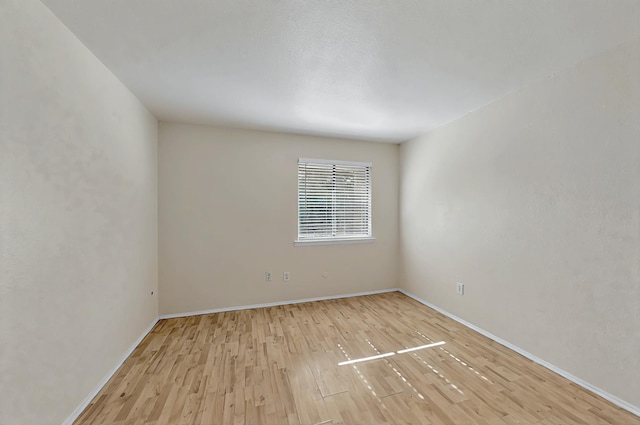 unfurnished room with baseboards and light wood-style flooring