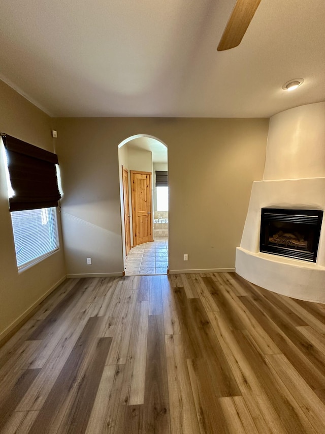 2638 Aloysia Ln NW, Albuquerque, NM 87104 - unfurnished living room with a ceiling fan, wood finished floors, baseboards, a fireplace, and arched walkways