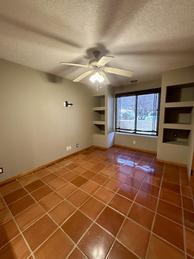 2638 Aloysia Ln NW, Albuquerque, NM 87104 - unfurnished room with built in shelves, a ceiling fan, a textured ceiling, tile patterned flooring, and baseboards