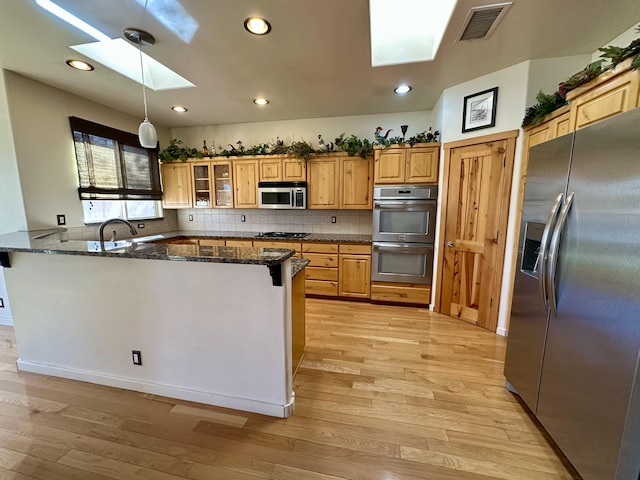 2638 Aloysia Ln NW, Albuquerque, NM 87104 - kitchen featuring visible vents, light wood-style flooring, a peninsula, appliances with stainless steel finishes, and a skylight