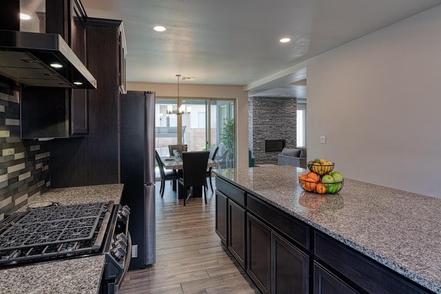 7754 Majesty Ct NW, Albuquerque, NM 87107 - kitchen with wall chimney range hood, a chandelier, freestanding refrigerator, range with gas stovetop, and light wood finished floors