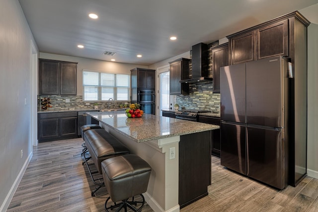 7754 Majesty Ct NW, Albuquerque, NM 87107 - kitchen featuring appliances with stainless steel finishes, wall chimney exhaust hood, a sink, dark brown cabinetry, and light stone counters