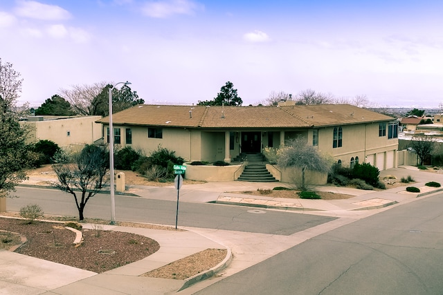 view of front facade featuring stucco siding, a tiled roof, an attached garage, and stairs