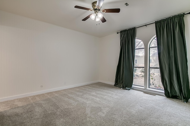 spare room with visible vents, baseboards, ceiling fan, and carpet flooring
