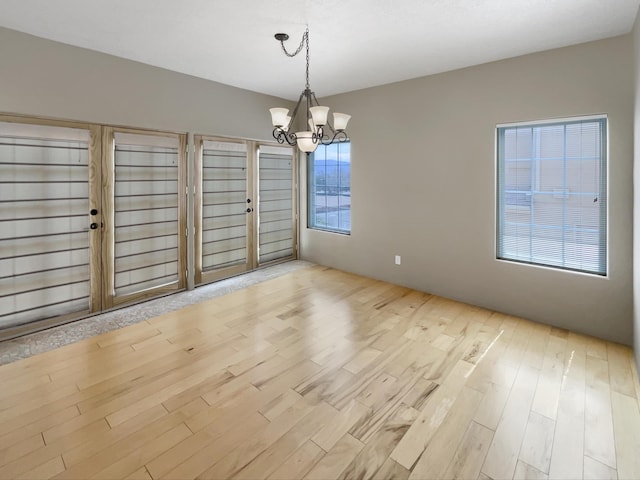 unfurnished dining area featuring an inviting chandelier and wood finished floors