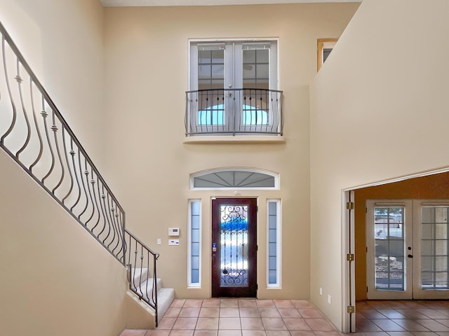 foyer entrance with tile patterned flooring, stairway, french doors, and a high ceiling