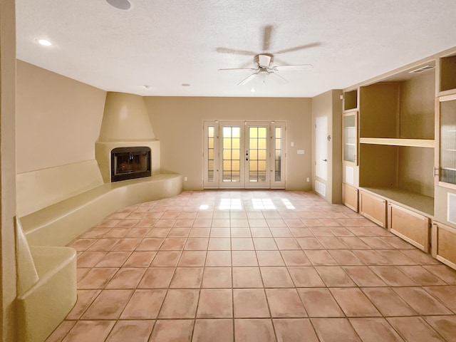 unfurnished living room with light tile patterned floors, a ceiling fan, visible vents, a textured ceiling, and a large fireplace