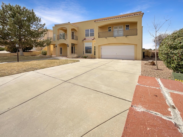 mediterranean / spanish-style house featuring fence, concrete driveway, stucco siding, a balcony, and an attached garage