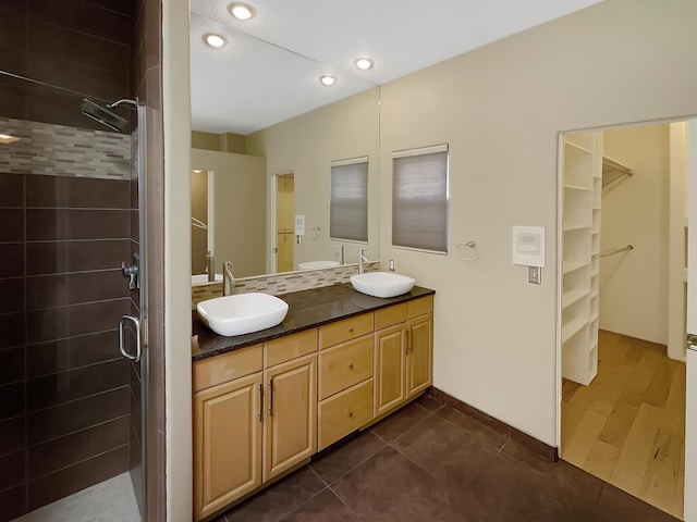 bathroom featuring a shower stall, double vanity, and a sink