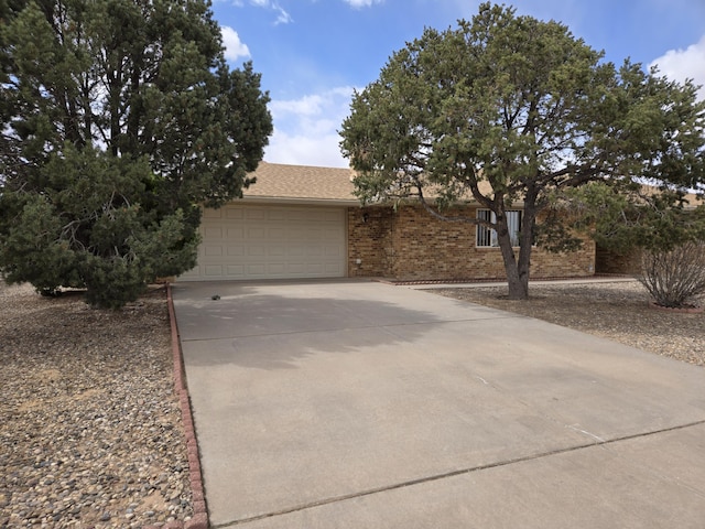 view of front of home with a garage, brick siding, and concrete driveway