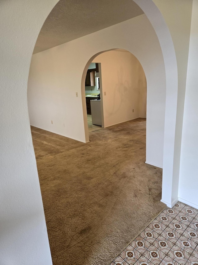 carpeted empty room with arched walkways