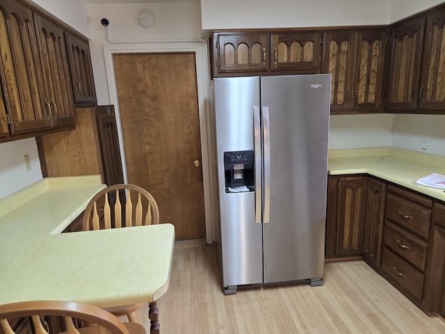 kitchen featuring light countertops, dark brown cabinets, stainless steel fridge with ice dispenser, and light wood finished floors