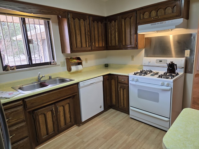 kitchen featuring white appliances, light countertops, under cabinet range hood, and a sink