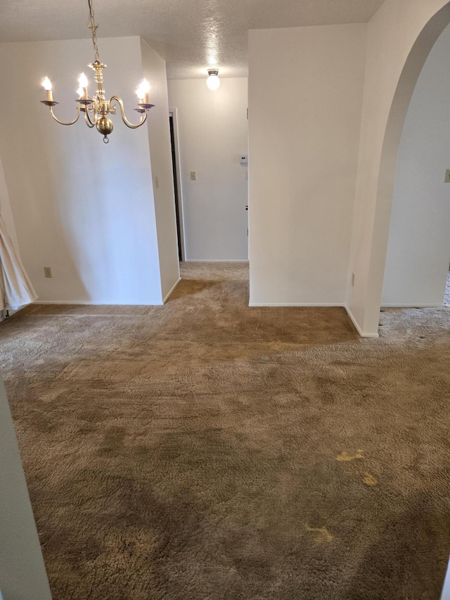 unfurnished room featuring arched walkways, a chandelier, and carpet flooring