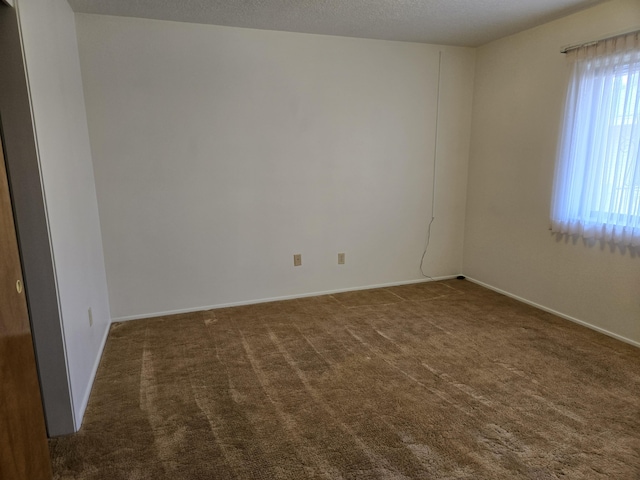 unfurnished room with baseboards, a textured ceiling, and carpet flooring
