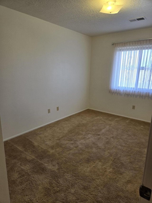 empty room with visible vents, a textured ceiling, baseboards, and dark colored carpet