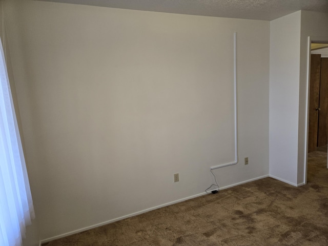 carpeted spare room featuring baseboards and a textured ceiling