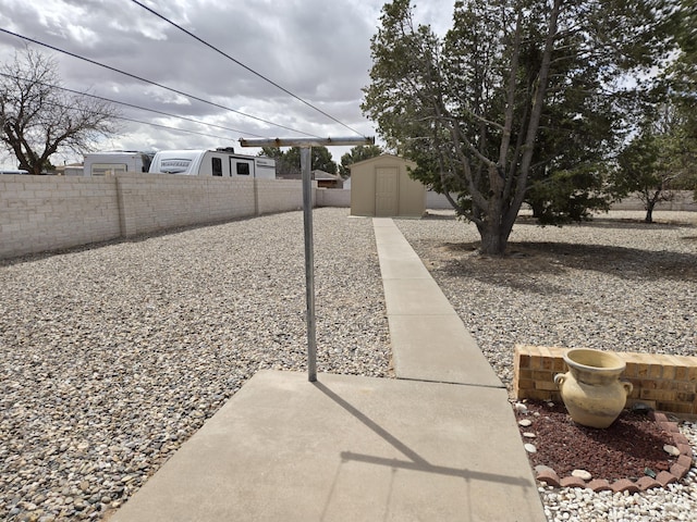 view of yard featuring a patio area, an outbuilding, a storage shed, and fence