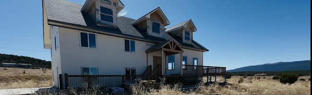 exterior space with a deck with mountain view and roof with shingles